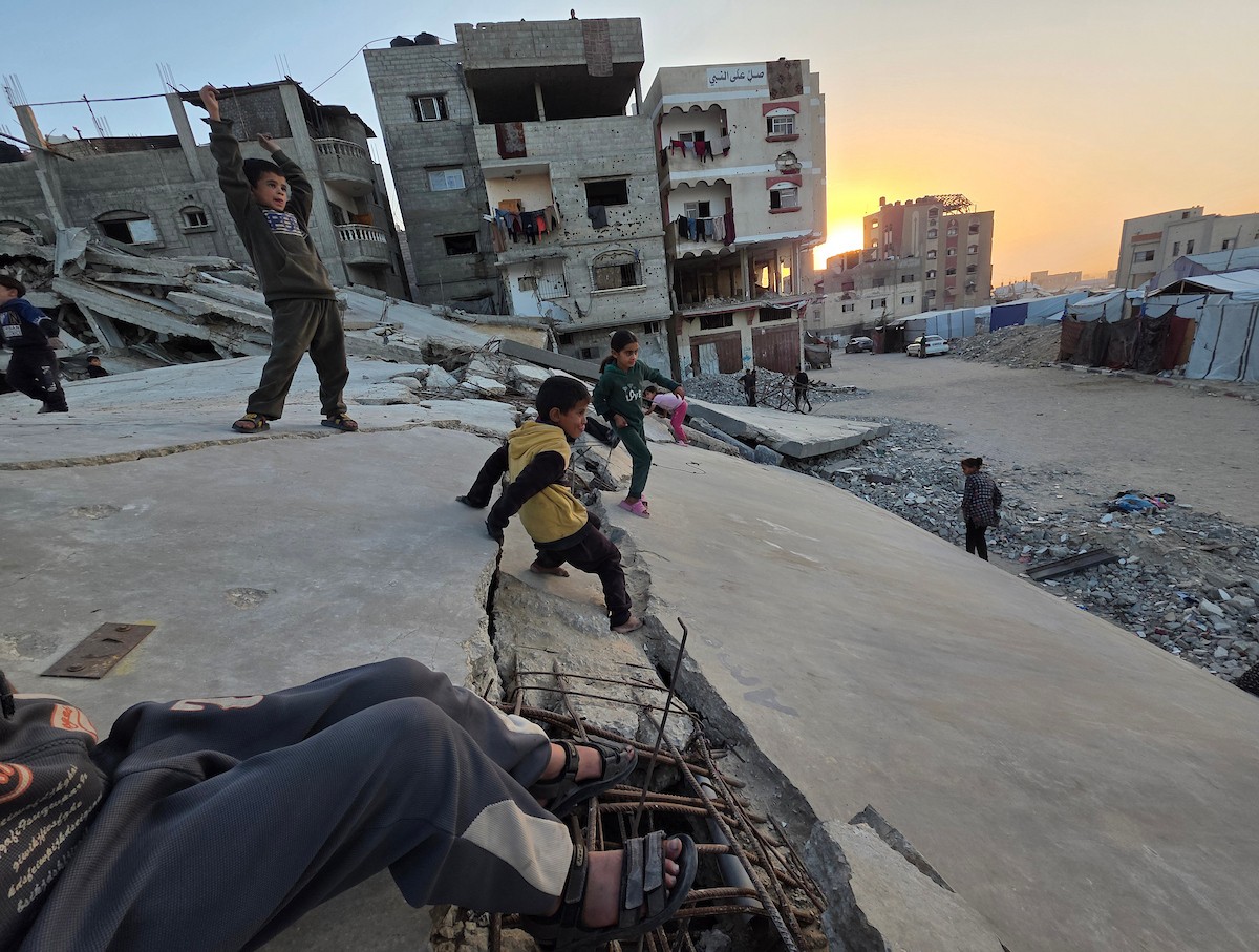 أطفال فلسطينيون يمشون على أسطح منازلهم المدمرة جراء الحرب الإسرائيلية في خان يونس (9).jpg