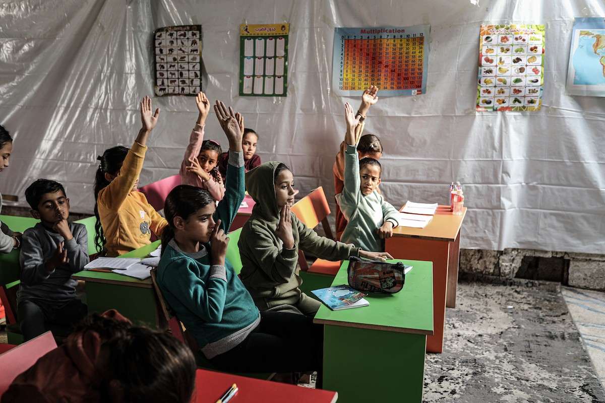أطفال فلسطينيون نازحون يحضرون درسًا داخل خيمة تُستخدم كفصل دراسي مؤقت في ملجأ بدير البلح (7).jpg