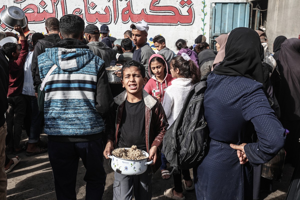 فلسطينيون في مخيم النصيرات وسط قطاع غزة يتلقون وجبات ساخنة من جمعية خيرية للنازحين