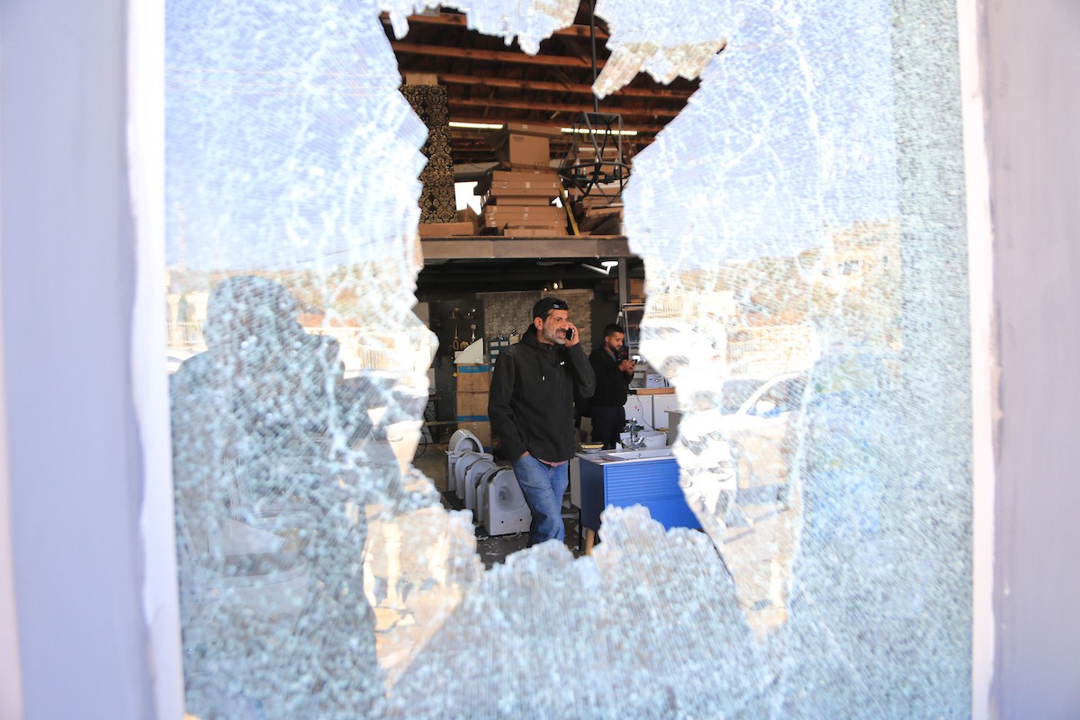 يتفقد الفلسطيني محمد مرقة متجره المتضرر بعد أن هاجمته مجموعة من المستوط.JPG