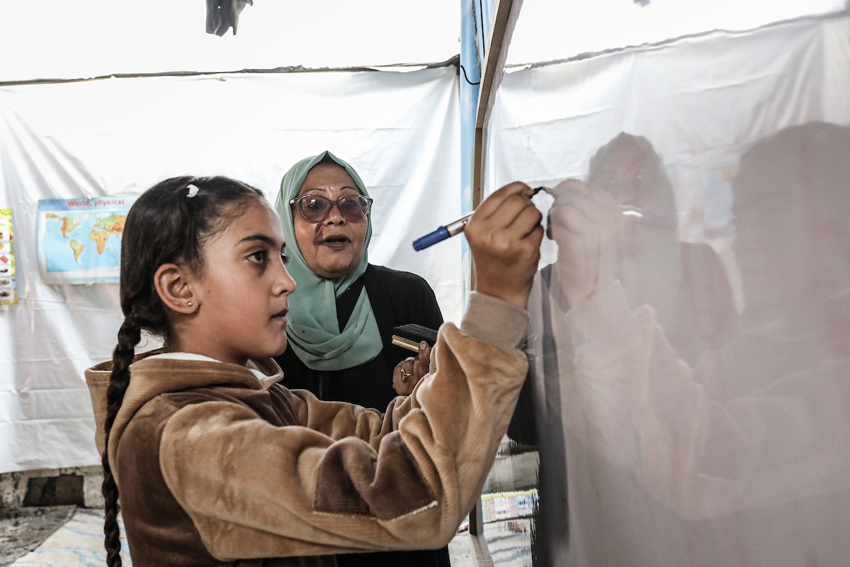 أطفال فلسطينيون نازحون يحضرون درسًا داخل خيمة تُستخدم كفصل دراسي مؤقت في ملجأ بدير البلح (4).jpg