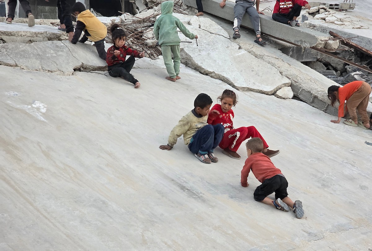 أطفال فلسطينيون يمشون على أسطح منازلهم المدمرة جراء الحرب الإسرائيلية في خان يونس (4).jpg