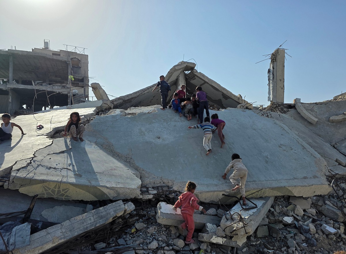 أطفال فلسطينيون يمشون على أسطح منازلهم المدمرة جراء الحرب الإسرائيلية في خان يونس (12).jpg