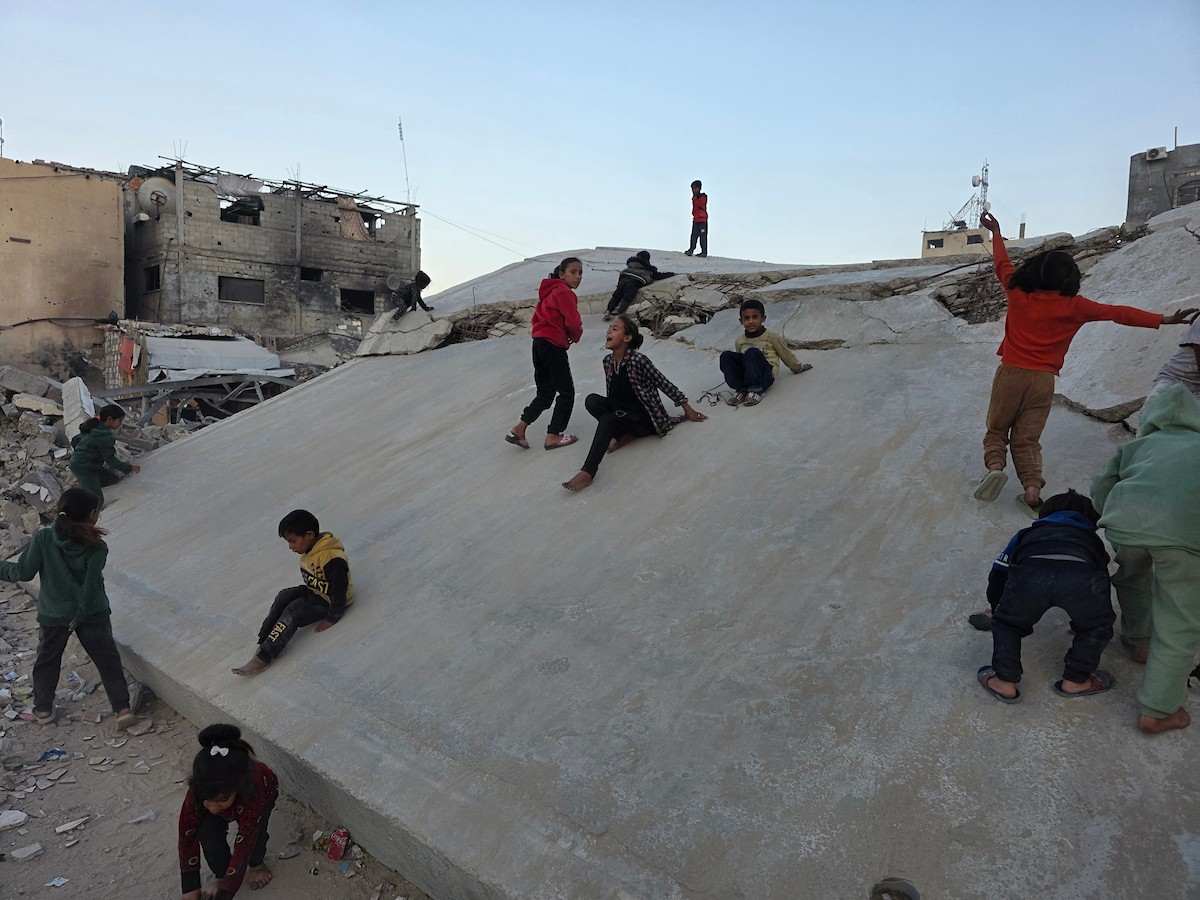 أطفال فلسطينيون يمشون على أسطح منازلهم المدمرة جراء الحرب الإسرائيلية في خان يونس (7).jpg