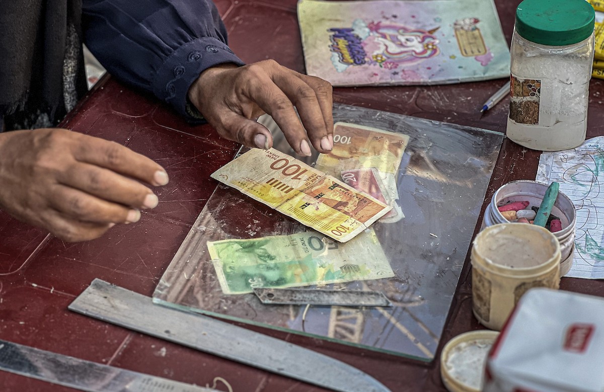 الفلسطينية منال السعيداني تُصلح أوراقًا نقدية قديمة ومهترئة في ظل نفاد العملة الصعبة في قطاع غزة (2).jpg