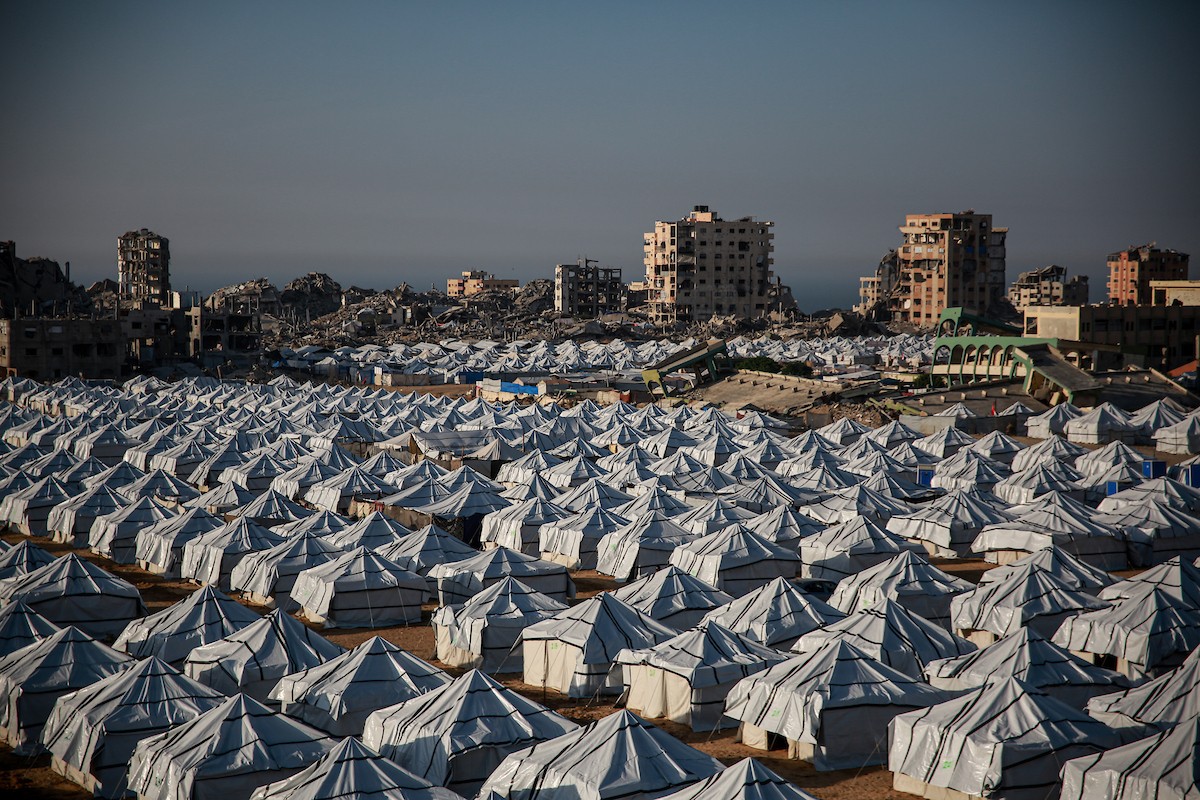 نازحون فلسطينيون يسيرون وسط ملاجئ مؤقتة شمال مدينة غزة