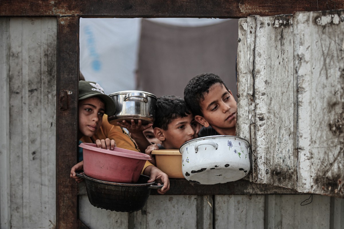 فلسطينيون في مخيم النصيرات وسط قطاع غزة يتلقون وجبات ساخنة من جمعية خيرية للنازحين