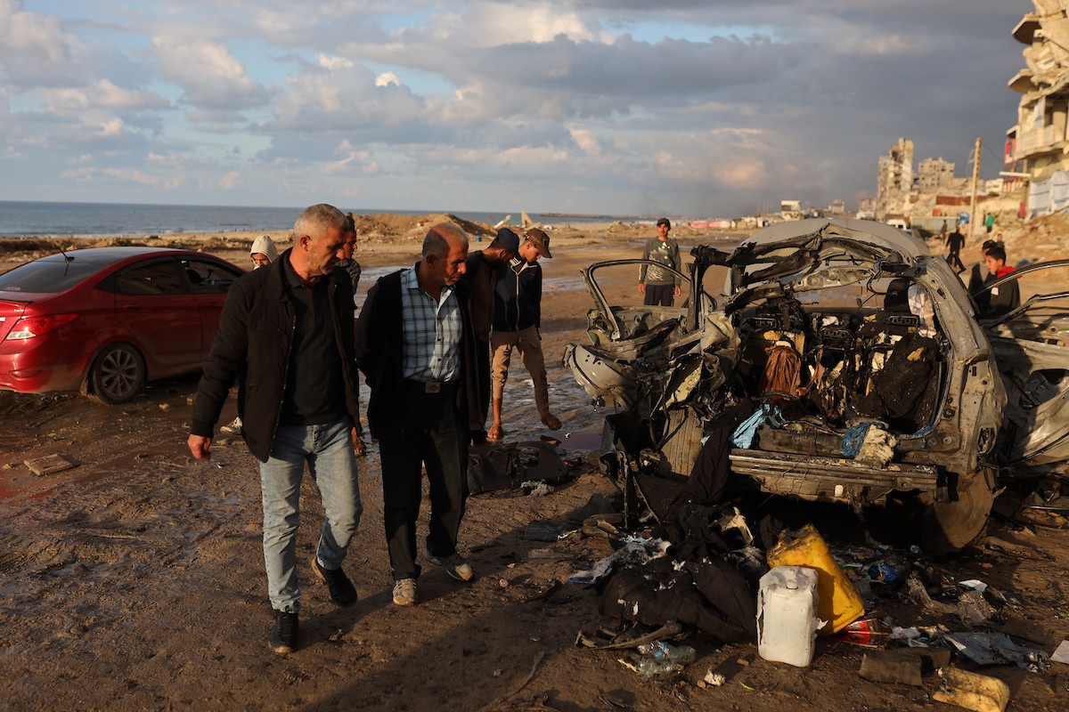 فلسطينيون يتفقدون موقع غارة إسرائيلية استهدفت سيارة على شارع لرشيد غرب مدينة غزة، 13 ديسمبر/كانون الأول 2025. صور: عمر أشتوي