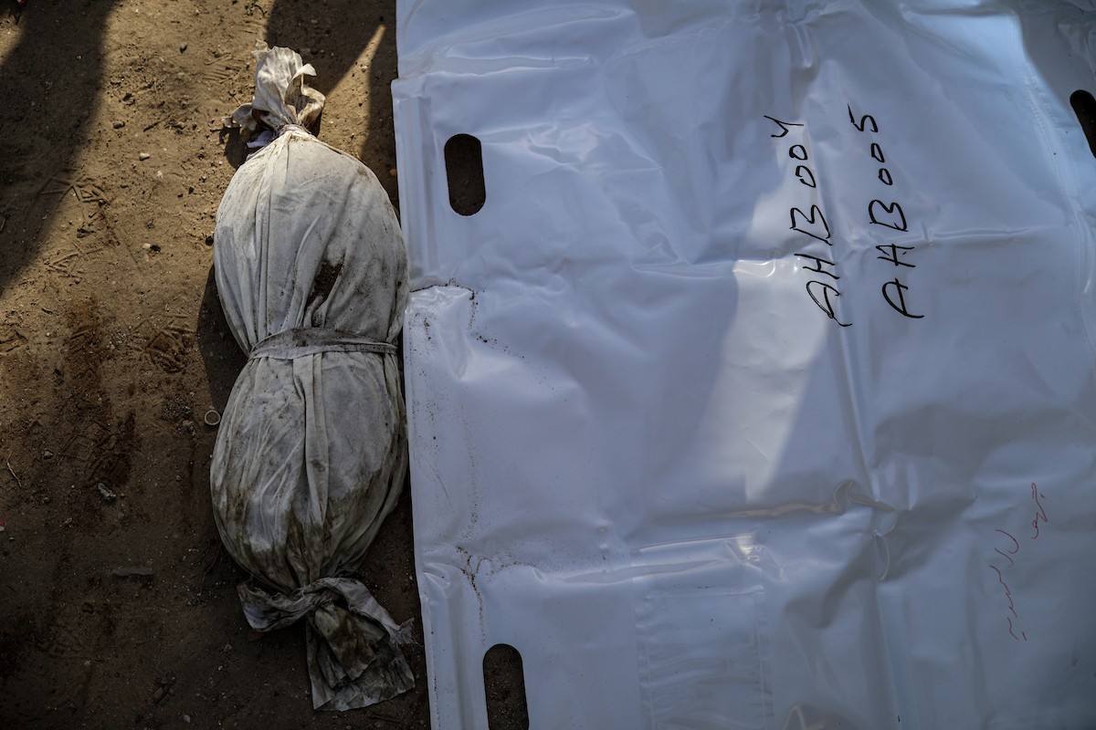 منقذون ومتطوعون فلسطينيون يستخرجون جثث ضحايا الحرب من مقبرة مؤقتة داخل المستشفى العربي المعمداني بمدينة غزة، ليعاد دفنها