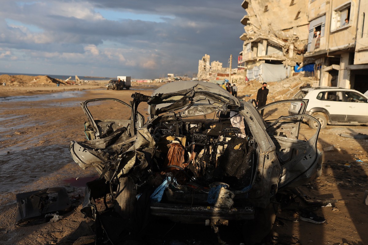 فلسطينيون يتفقدون موقع غارة إسرائيلية استهدفت سيارة على شارع لرشيد غرب مدينة غزة، 13 ديسمبر/كانون الأول 2025. صور: عمر أشتوي