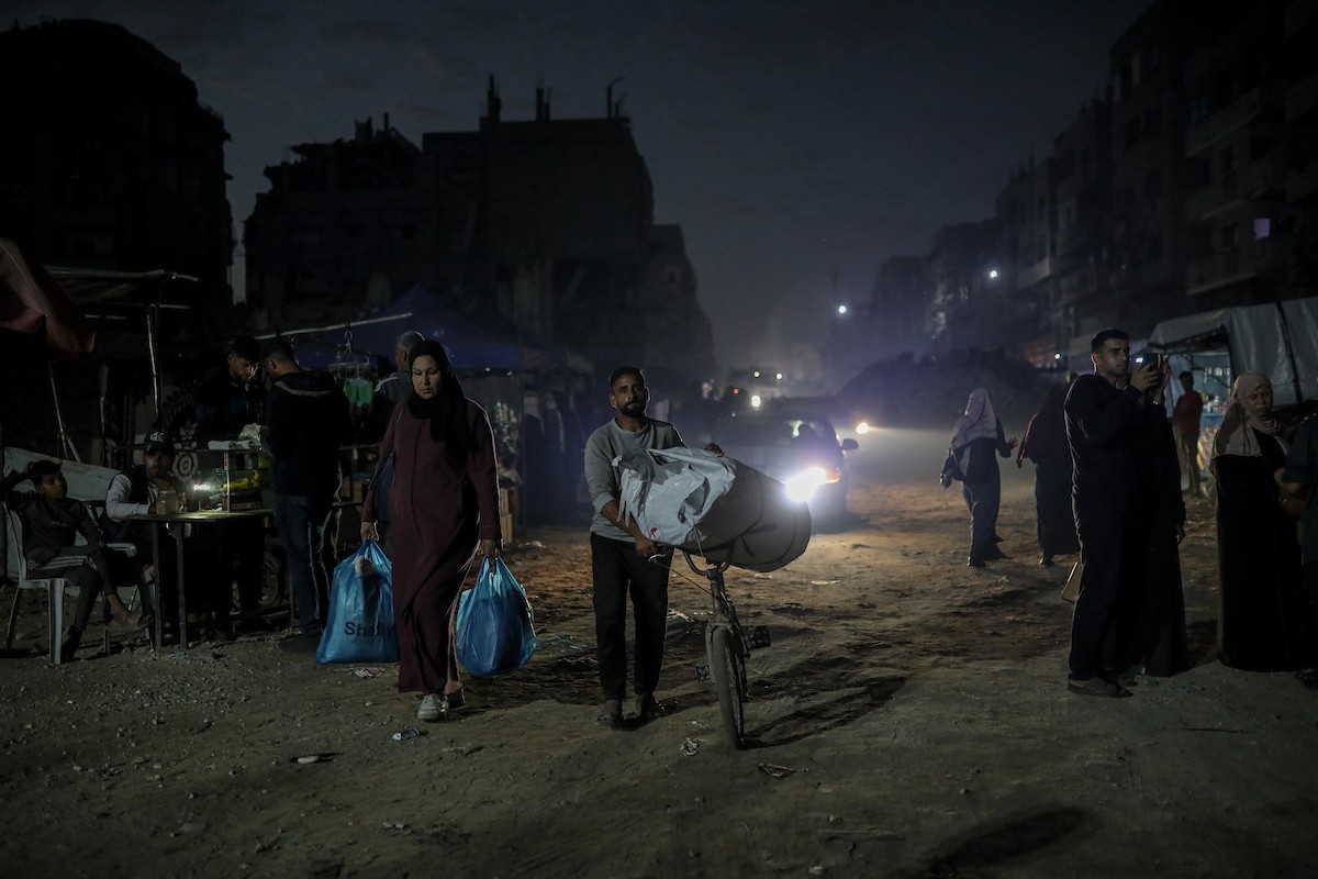 يعيش الفلسطينيون حياتهم اليومية ليلاً في خيام نصبت فوق أنقاض المباني المدمرة في حي الشيخ رضوان وسط مدينة غزة، 5 ديسمبر/كانون الأول 2025.تصوير: عمر أشتوي