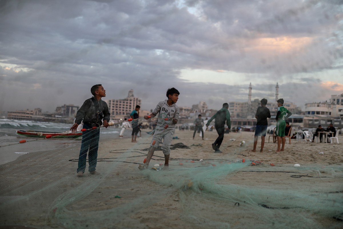يقضي فلسطينيون نازحون وقتًا على الشاطئ مقابل خيامهم الممتدة على طول ميناء غزة، في غزة، 5 ديسمبر/كانون الأول 2025. تصوير: عمر أشتوي