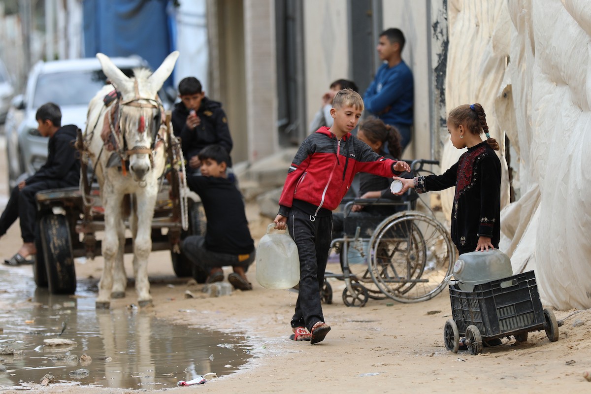 يتجمع الفلسطينيون لتلقي مياه الشرب مجانًا في مخيم البريج للاجئين، في ظل تفاقم أزمة نقص المياه وتدهور البنية التحتية، 21 ديسمبر/كانون الأول 2025. صورة: رمزي أبو عامر