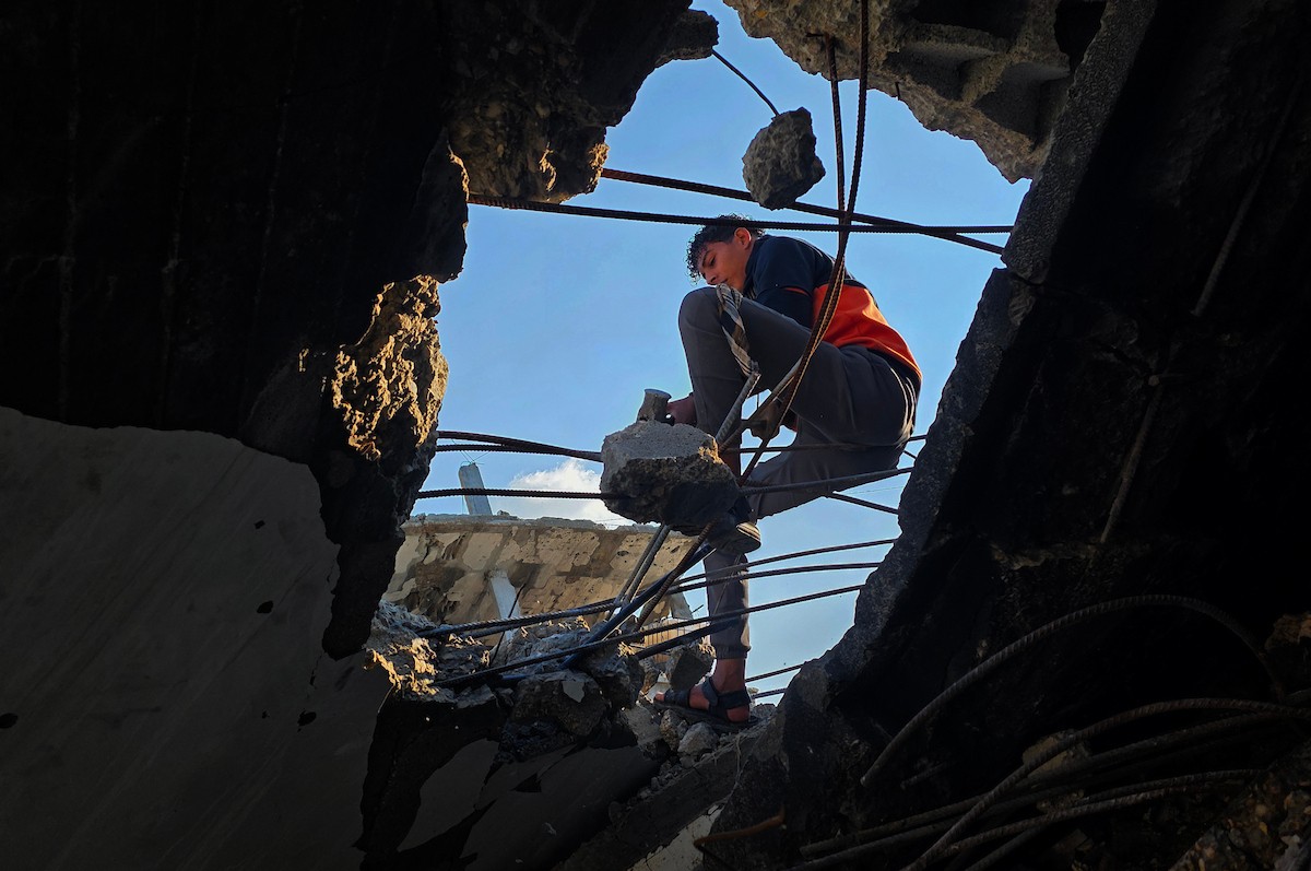 الفلسطيني هشام أبو عية يبني مأوى مؤقت لعائلته المكونة من ثمانية أفراد باستخدام قضبان حديدية استخرجها من أنقاض منزله الذي دُمر في هجمات إسرائيلية بمنطقة بطن السمين في خان يونس،  19 ديسمبر/كانون الأول 2025. تصوير: طارق محمد/ (APA )