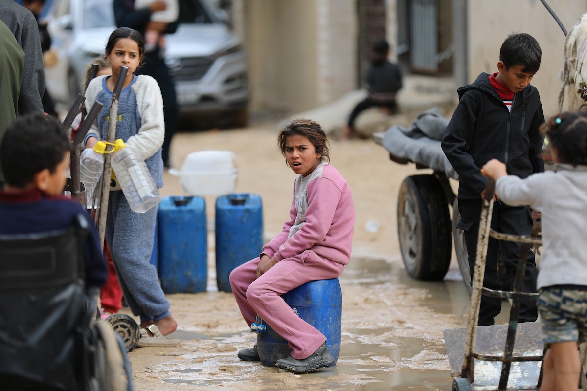 يتجمع الفلسطينيون لتلقي مياه الشرب مجانًا في مخيم البريج للاجئين، في ظل تفاقم أزمة نقص المياه وتدهور البنية التحتية، 21 ديسمبر/كانون الأول 2025. صورة: رمزي أبو عامر