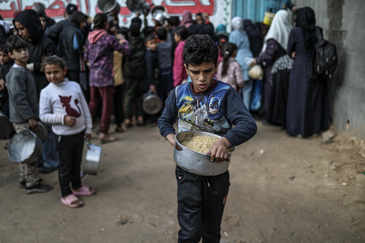 يصطفّ فلسطينيون لتلقّي الطعام من مطبخ خيري في تجمع للنازحين بمخيم النصيرات للاجئين، وسط قطاع غزة. ١٧ ديسمبر/كانون الأول ٢٠٢٥. تصوير: رمزي أبو عامر / (apa)