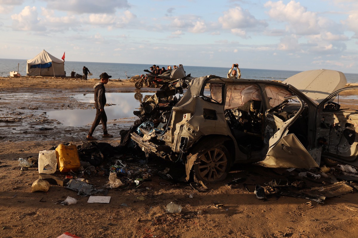 فلسطينيون يتفقدون موقع غارة إسرائيلية استهدفت سيارة على شارع لرشيد غرب مدينة غزة، 13 ديسمبر/كانون الأول 2025. صور: عمر أشتوي