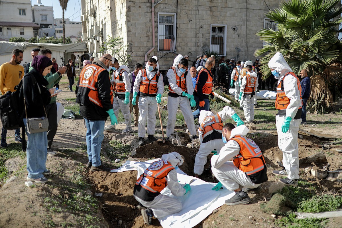 منقذون ومتطوعون فلسطينيون يستخرجون جثث ضحايا الحرب من مقبرة مؤقتة داخل المستشفى العربي المعمداني بمدينة غزة، ليعاد دفنها