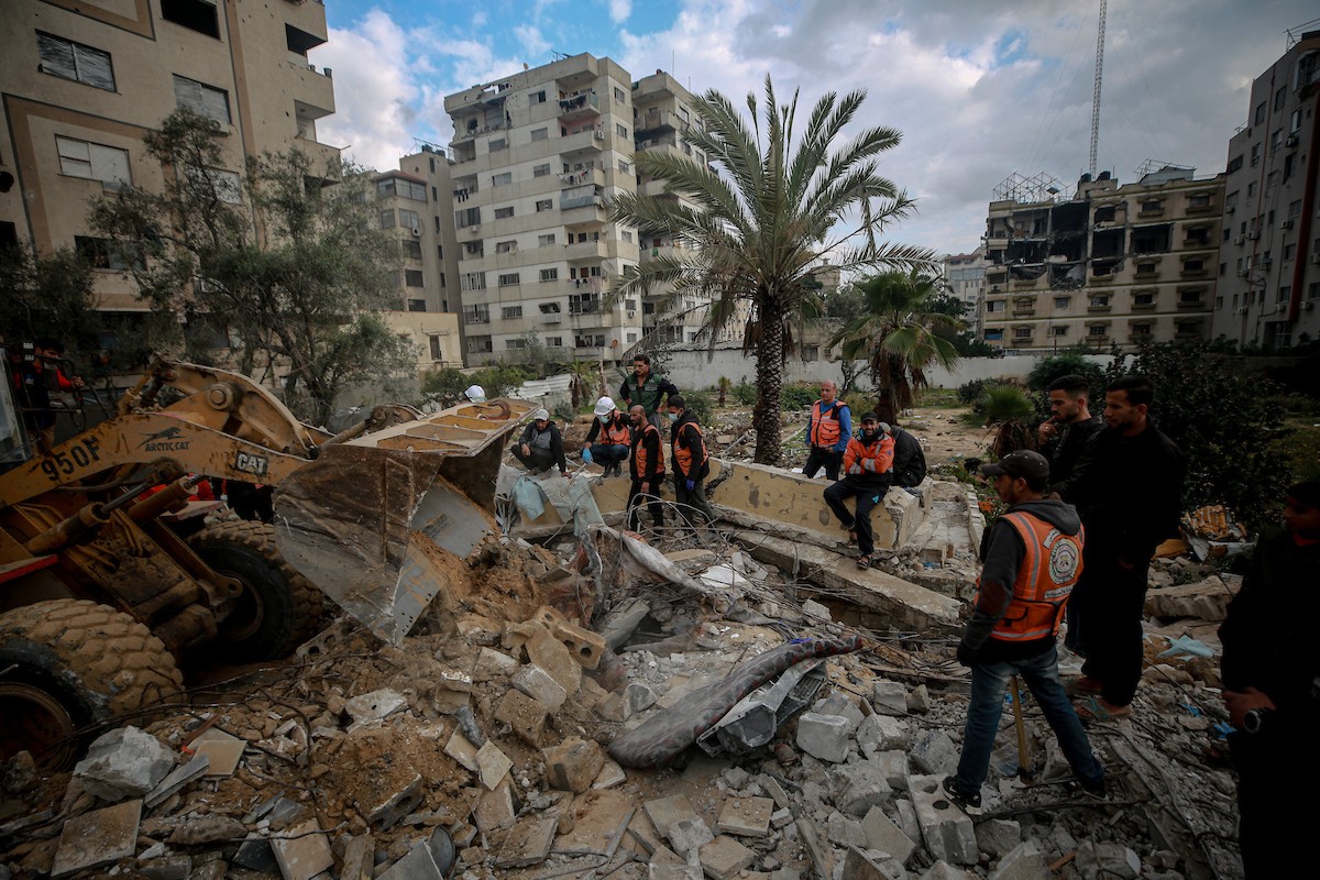 عمال الدفاع المدني الفلسطيني يبحثون عن جثث في مبنى منهار يعود لعائلة سالم، استُهدف بغارات إسرائيلية في بداية الحرب، في شارع الجلاء بمدينة غزة، يوم الاثنين 15 ديسمبر/كانون الأول 2025. صورة: عمر أشتوي