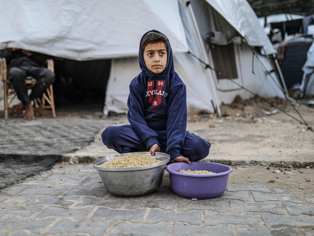 يصطفّ فلسطينيون لتلقّي الطعام من مطبخ خيري في تجمع للنازحين بمخيم النصيرات للاجئين، وسط قطاع غزة. ١٧ ديسمبر/كانون الأول ٢٠٢٥. تصوير: رمزي أبو عامر / (apa)