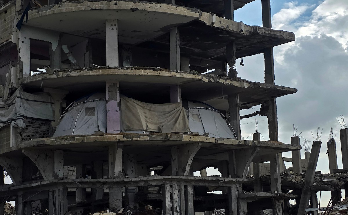 عائلة فلسطينية تحتمي من برد الشتاء القارس في خيمة نصبتها فوق منزلها المدمر قرب الخط الأصفر في خان يونس، جنوب قطاع غزة، ١٧ ديسمبر/كانون الأول ٢٠٢٥. تصوير: طارق محمد/وكالة الأنباء الفلسطينية (APA )