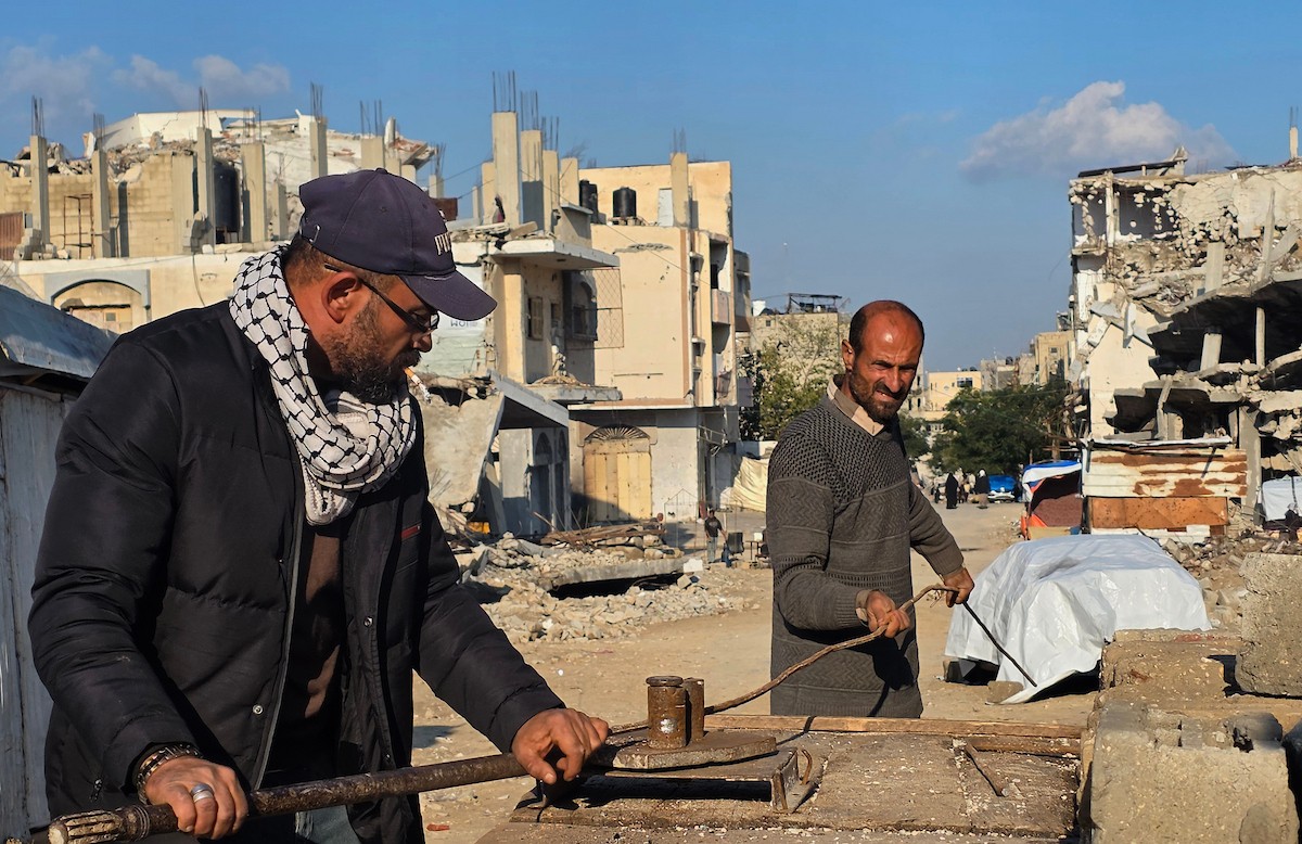 الفلسطيني هشام أبو عية يبني مأوى مؤقت لعائلته المكونة من ثمانية أفراد باستخدام قضبان حديدية استخرجها من أنقاض منزله الذي دُمر في هجمات إسرائيلية بمنطقة بطن السمين في خان يونس،  19 ديسمبر/كانون الأول 2025. تصوير: طارق محمد/ (APA )