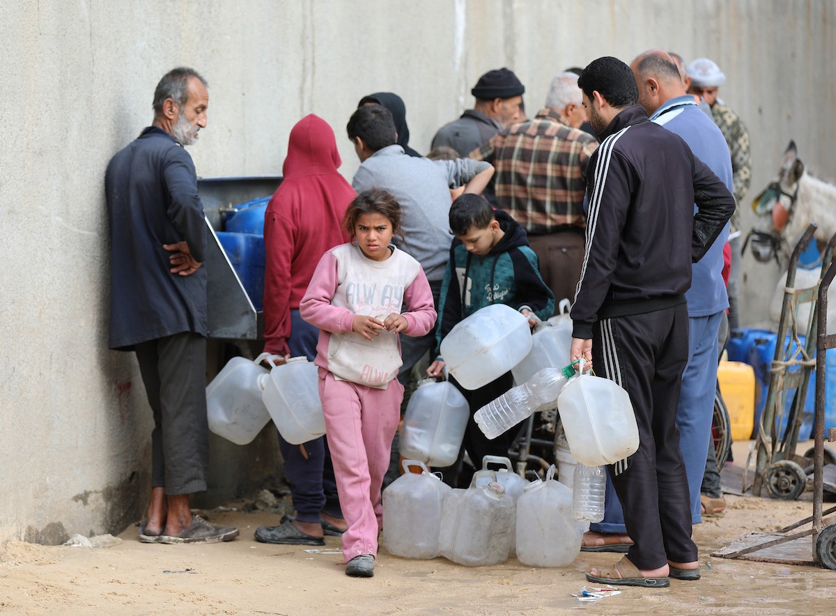 يتجمع الفلسطينيون لتلقي مياه الشرب مجانًا في مخيم البريج للاجئين، في ظل تفاقم أزمة نقص المياه وتدهور البنية التحتية، 21 ديسمبر/كانون الأول 2025. صورة: رمزي أبو عامر