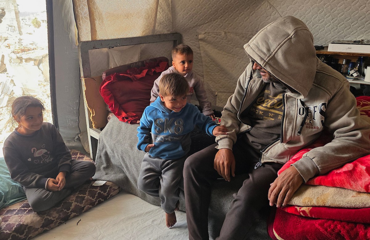 عائلة فلسطينية تحتمي من برد الشتاء القارس في خيمة نصبتها فوق منزلها المدمر قرب الخط الأصفر في خان يونس، جنوب قطاع غزة، ١٧ ديسمبر/كانون الأول ٢٠٢٥. تصوير: طارق محمد/وكالة الأنباء الفلسطينية (APA )