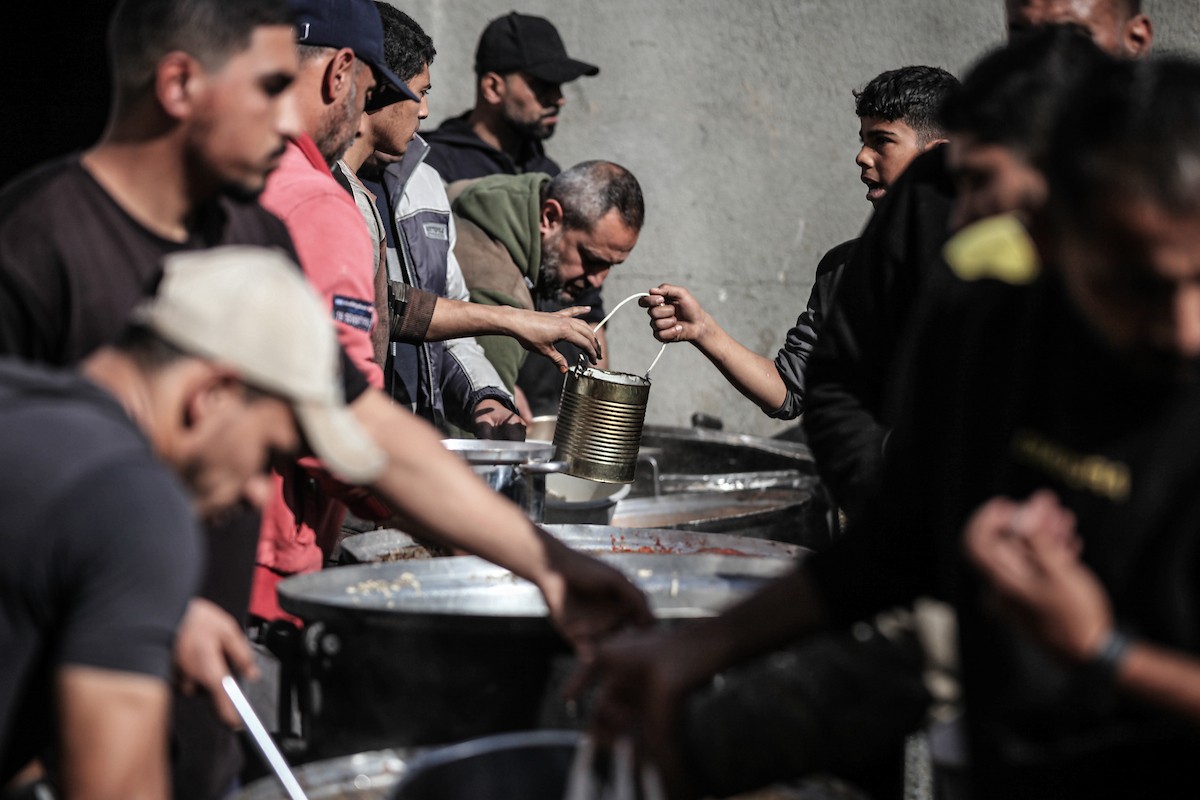 يتلقى فلسطينيون في مخيم النصيرات وسط قطاع غزة وجبات ساخنة من جمعية خيرية تُعنى بالنازحين جراء الهجمات الإسرائيلية، بينما يتجمع حشد كبير، يضم نساءً وأطفالاً، خلال عملية التوزيع، في 30 ديسمبر/كانون الأول 2025. صورة: معز صالحي