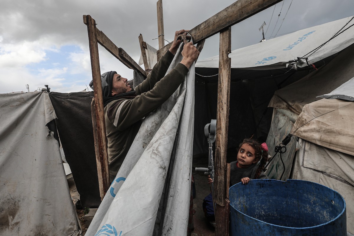 أحمد أبو ليلى أب لخمسة أطفال أصيب في الحرب  يحاول إصلاح خيمته بعد أن تضررت جراء الأمطار الغزيرة والرياح العاتية التي اجتاحت مخيم النصيرات وسط قطاع غزة، 28 ديسمبر/كانون الأول 2025.تصوير: معز صالحي