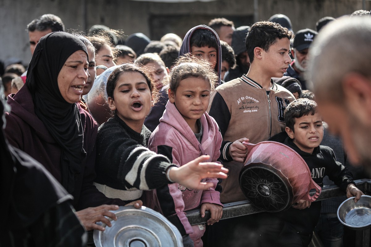 يتلقى فلسطينيون في مخيم النصيرات وسط قطاع غزة وجبات ساخنة من جمعية خيرية تُعنى بالنازحين جراء الهجمات الإسرائيلية، بينما يتجمع حشد كبير، يضم نساءً وأطفالاً، خلال عملية التوزيع، في 30 ديسمبر/كانون الأول 2025. صورة: معز صالحي