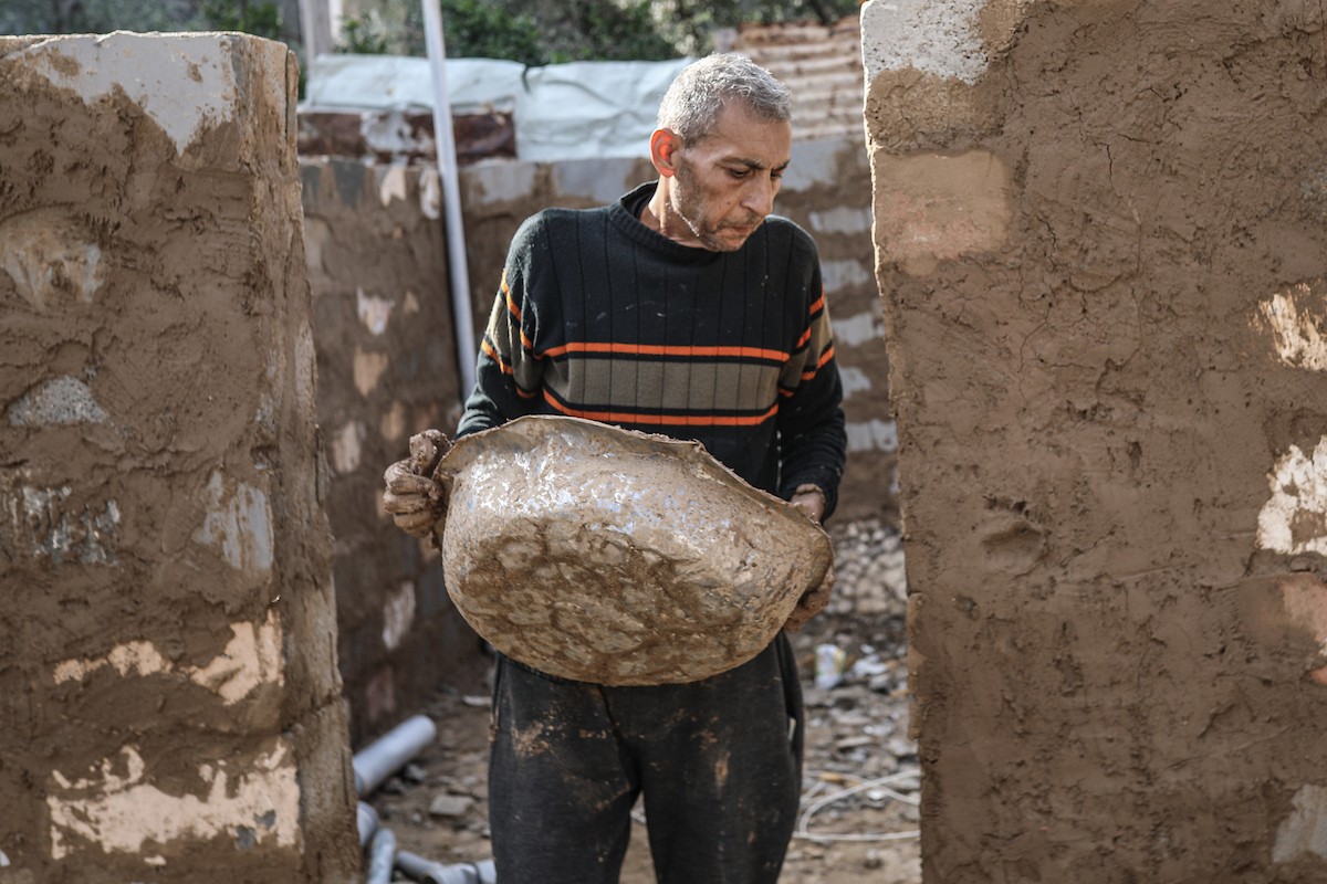 الفلسطيني أحمد المبحوح، مريض سرطان، يبني منزلاً طينياً بيديه في مخيم البريج للاجئين وسط قطاع غزة، 15 ديسمبر/كانون الأول 2025. عدسة: رمزي أبو عامر