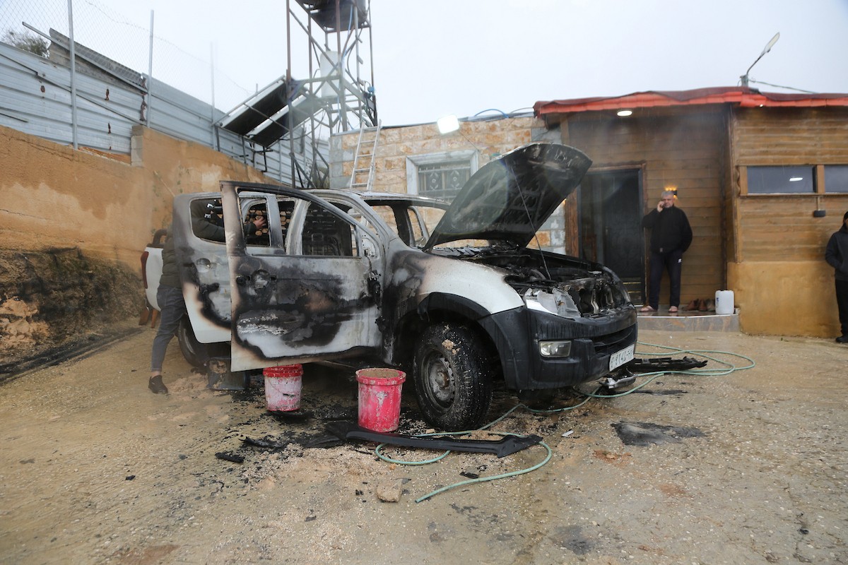 فلسطينيون يقفون في موقع حريق سيارة أشعله مستوطنون إسرائيليون في بلدة حوارة، جنوب نابلس في الضفة الغربية، 28 ديسمبر/كانون الأول 2025. صورة: محمد ناصر