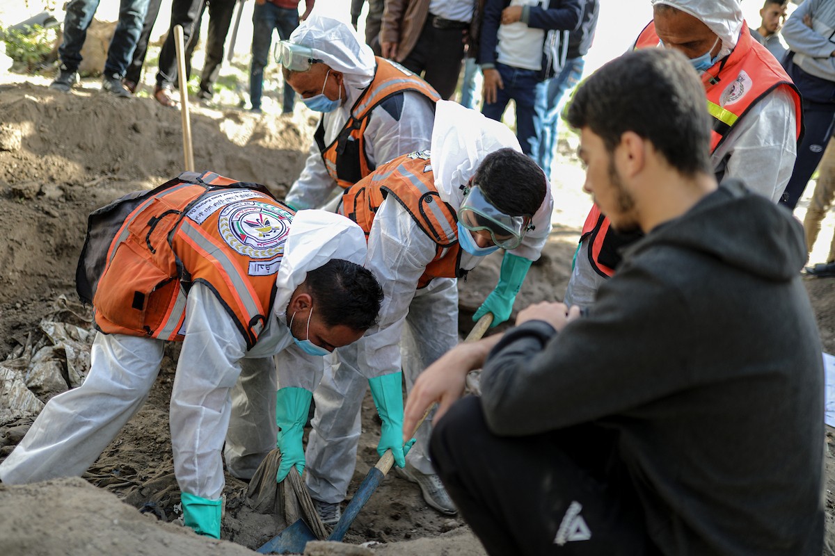 منقذون ومتطوعون فلسطينيون يستخرجون جثث ضحايا الحرب من مقبرة مؤقتة داخل المستشفى العربي المعمداني بمدينة غزة، ليعاد دفنها