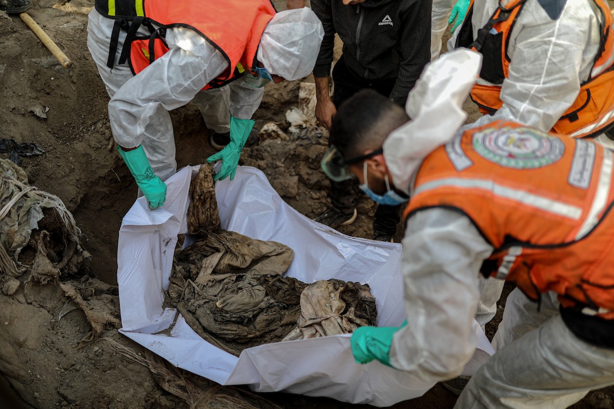 منقذون ومتطوعون فلسطينيون يستخرجون جثث ضحايا الحرب من مقبرة مؤقتة داخل المستشفى العربي المعمداني بمدينة غزة، ليعاد دفنها