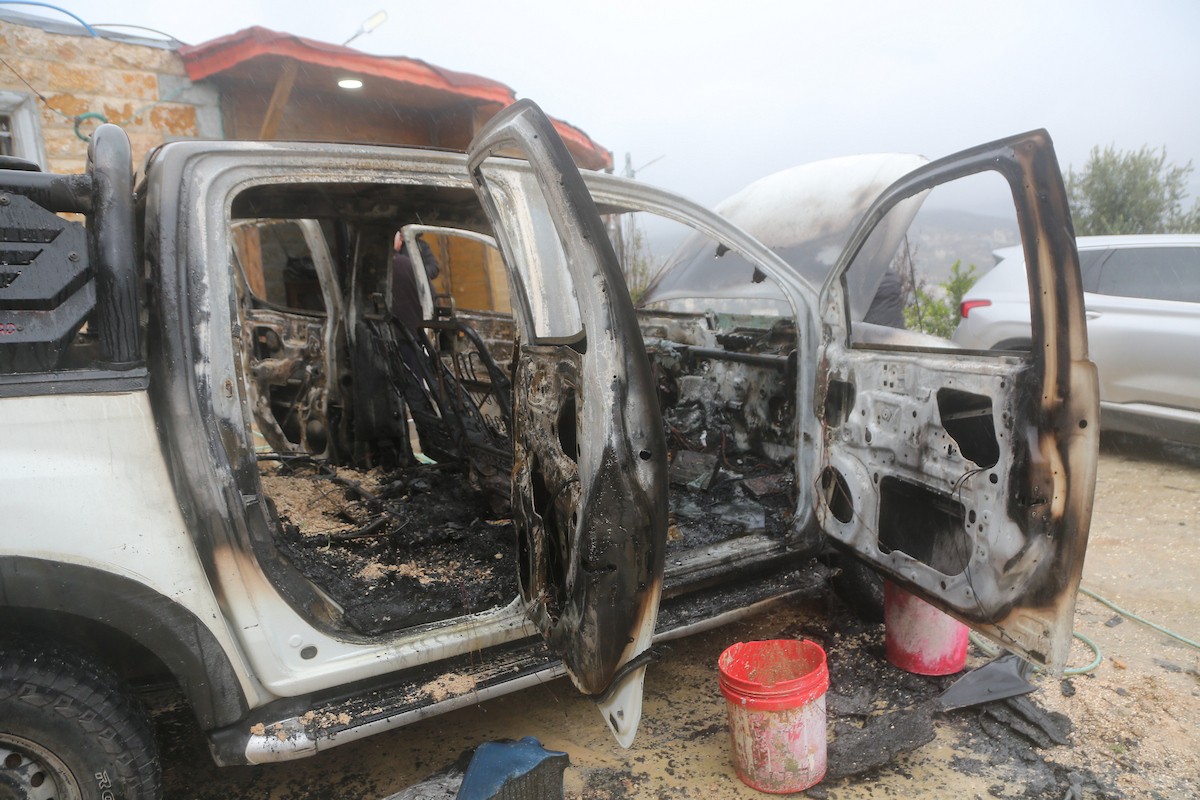 فلسطينيون يقفون في موقع حريق سيارة أشعله مستوطنون إسرائيليون في بلدة حوارة، جنوب نابلس في الضفة الغربية، 28 ديسمبر/كانون الأول 2025. صورة: محمد ناصر