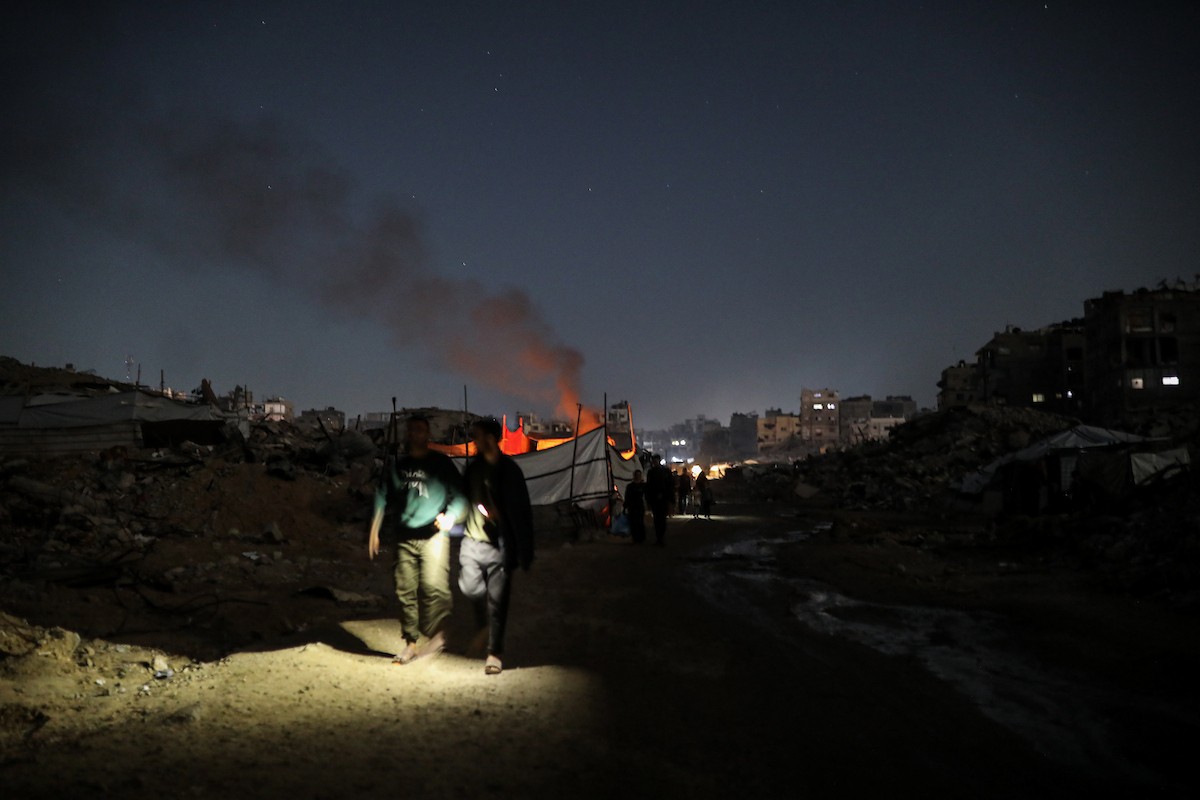 يعيش الفلسطينيون حياتهم اليومية ليلاً في خيام نصبت فوق أنقاض المباني المدمرة في حي الشيخ رضوان وسط مدينة غزة، 5 ديسمبر/كانون الأول 2025.تصوير: عمر أشتوي