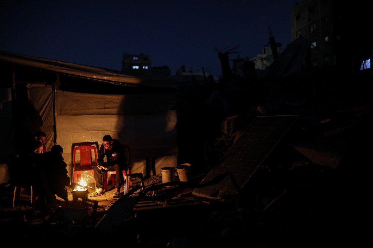 يعيش الفلسطينيون حياتهم اليومية ليلاً في خيام نصبت فوق أنقاض المباني المدمرة في حي الشيخ رضوان وسط مدينة غزة، 5 ديسمبر/كانون الأول 2025.تصوير: عمر أشتوي