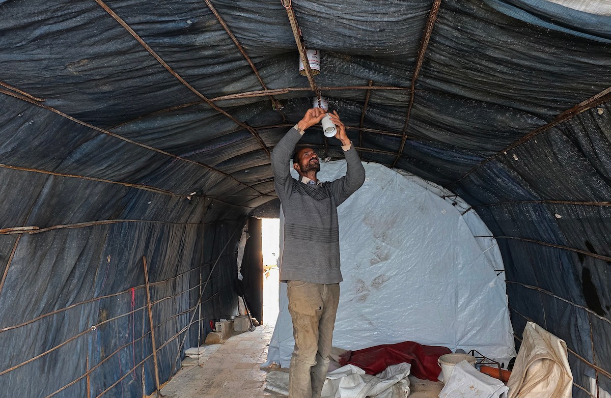 الفلسطيني هشام أبو عية يبني مأوى مؤقت لعائلته المكونة من ثمانية أفراد باستخدام قضبان حديدية استخرجها من أنقاض منزله الذي دُمر في هجمات إسرائيلية بمنطقة بطن السمين في خان يونس،  19 ديسمبر/كانون الأول 2025. تصوير: طارق محمد/ (APA )