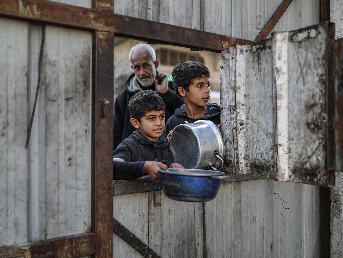 يصطفّ فلسطينيون لتلقّي الطعام من مطبخ خيري في تجمع للنازحين بمخيم النصيرات للاجئين، وسط قطاع غزة. ١٧ ديسمبر/كانون الأول ٢٠٢٥. تصوير: رمزي أبو عامر / (apa)