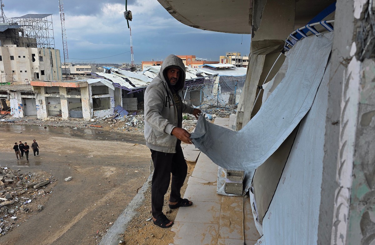 عائلة فلسطينية تحتمي من برد الشتاء القارس في خيمة نصبتها فوق منزلها المدمر قرب الخط الأصفر في خان يونس، جنوب قطاع غزة، ١٧ ديسمبر/كانون الأول ٢٠٢٥. تصوير: طارق محمد/وكالة الأنباء الفلسطينية (APA )