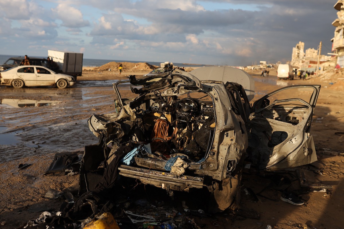 فلسطينيون يتفقدون موقع غارة إسرائيلية استهدفت سيارة على شارع لرشيد غرب مدينة غزة، 13 ديسمبر/كانون الأول 2025. صور: عمر أشتوي