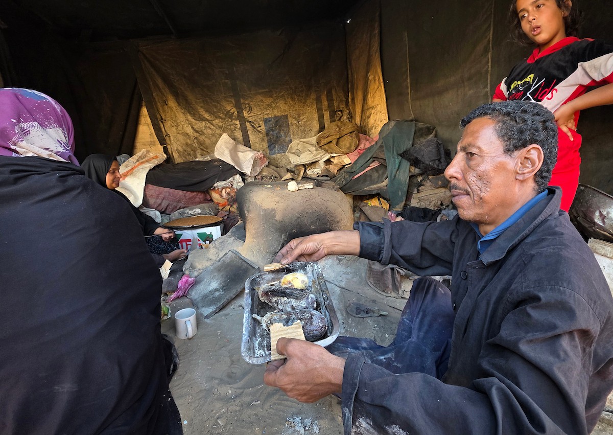 يتجمع فلسطينيون حول أفران طينية مؤقتة لطهي الطعام في قطاع غزة، بعد عشرة أسابيع من وقف إطلاق النار، في ظل شحّ غاز الطهي بسبب القيود الإسرائيلية على دخوله إلى القطاع