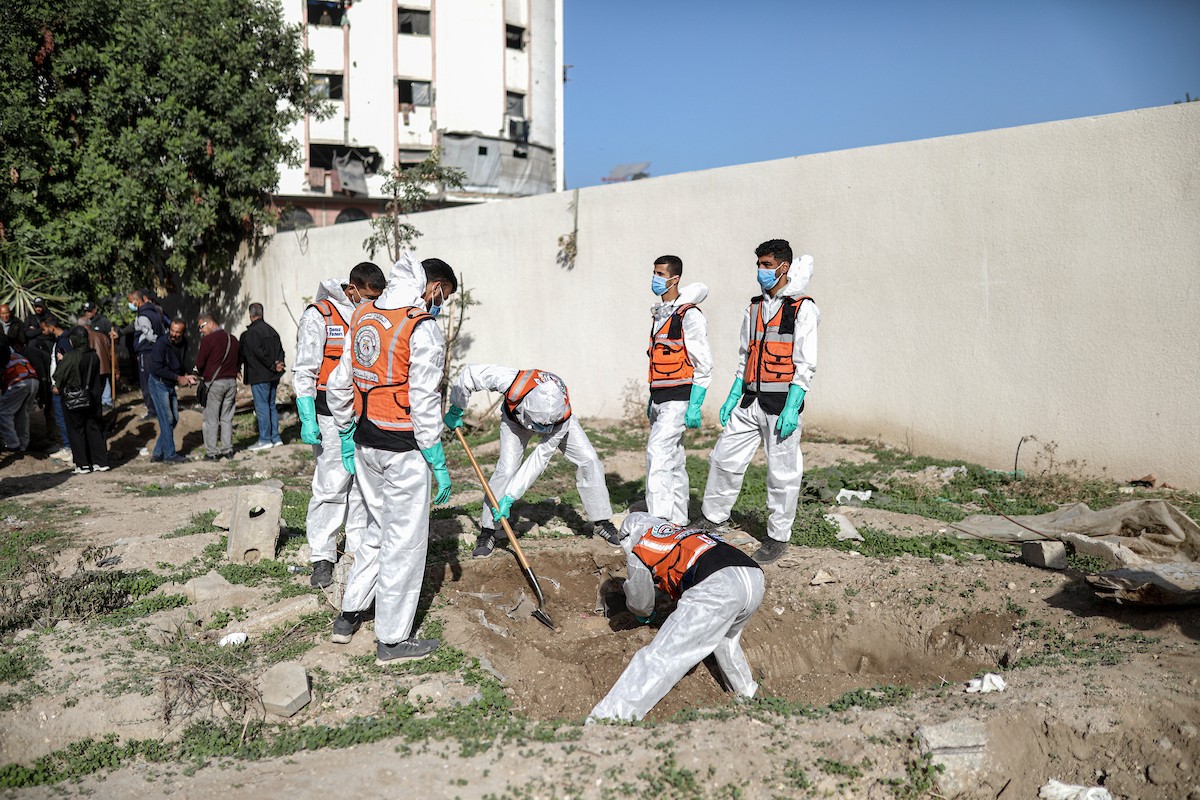 منقذون ومتطوعون فلسطينيون يستخرجون جثث ضحايا الحرب من مقبرة مؤقتة داخل المستشفى العربي المعمداني بمدينة غزة، ليعاد دفنها