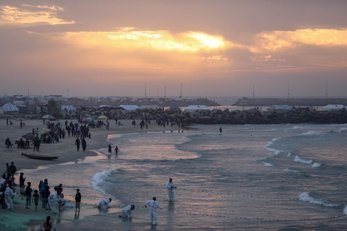 يقضي فلسطينيون نازحون وقتًا على الشاطئ مقابل خيامهم الممتدة على طول ميناء غزة، في غزة، 5 ديسمبر/كانون الأول 2025. تصوير: عمر أشتوي