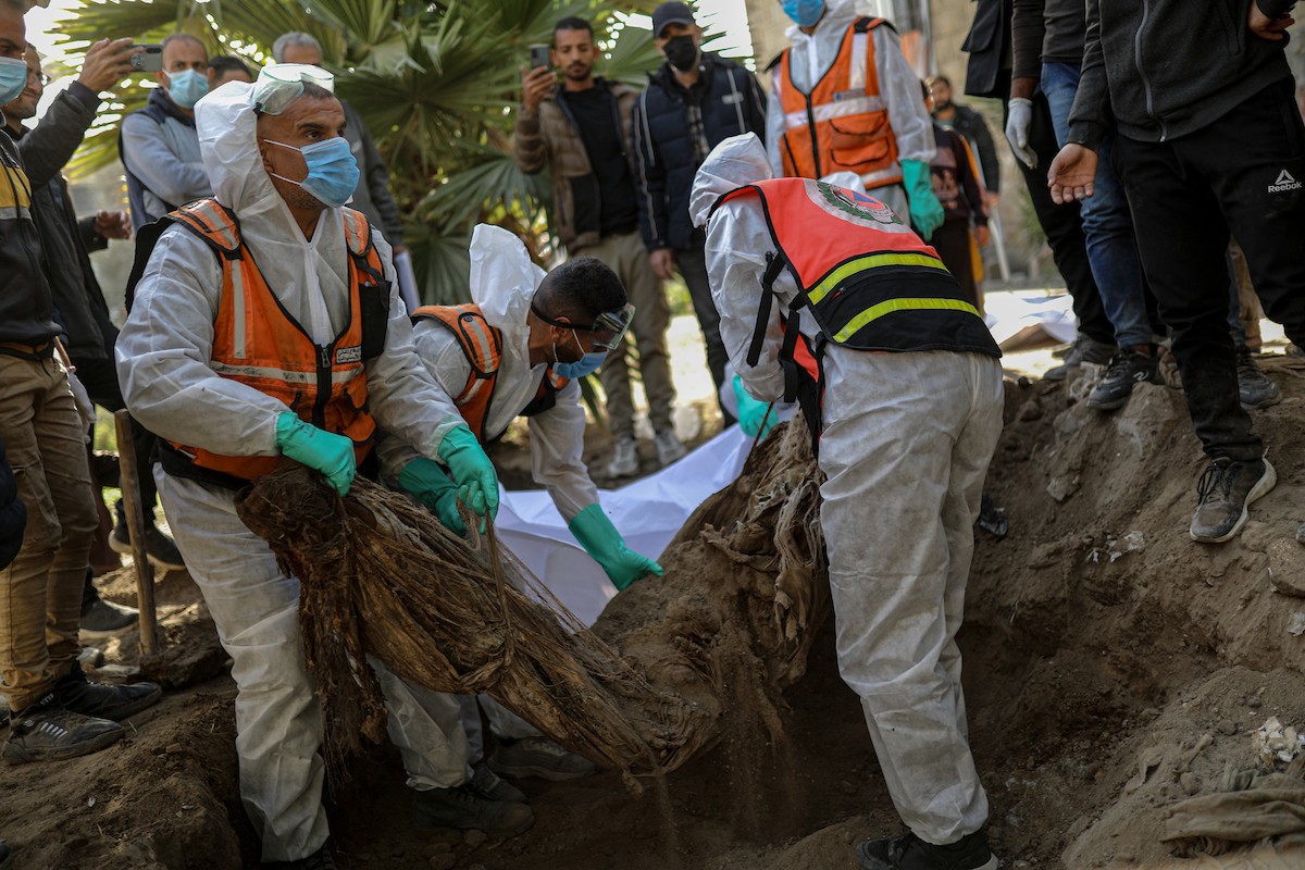 منقذون ومتطوعون فلسطينيون يستخرجون جثث ضحايا الحرب من مقبرة مؤقتة داخل المستشفى العربي المعمداني بمدينة غزة، ليعاد دفنها