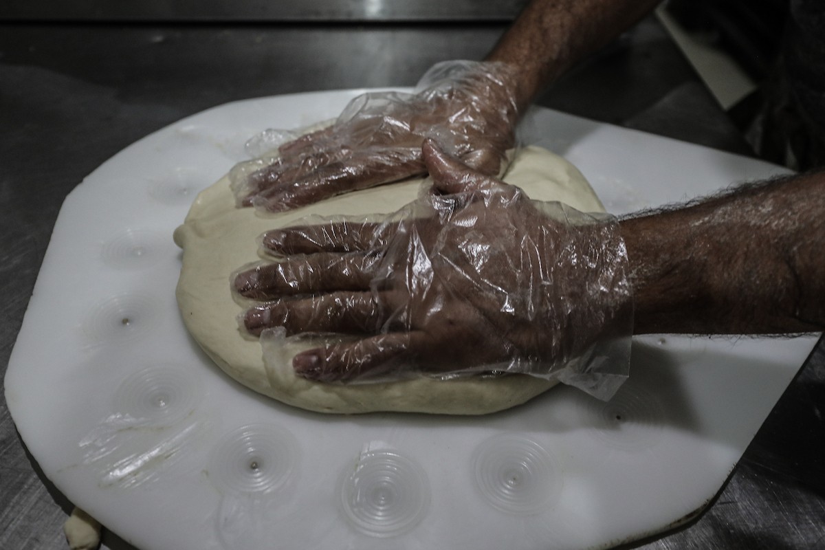 عمال فلسطينيون يعيدون تشغيل أحد أقدم المخابز في مخيم النصيرات للاجئين بعد إغلاقه لمدة عامين بسبب الحرب.jpg