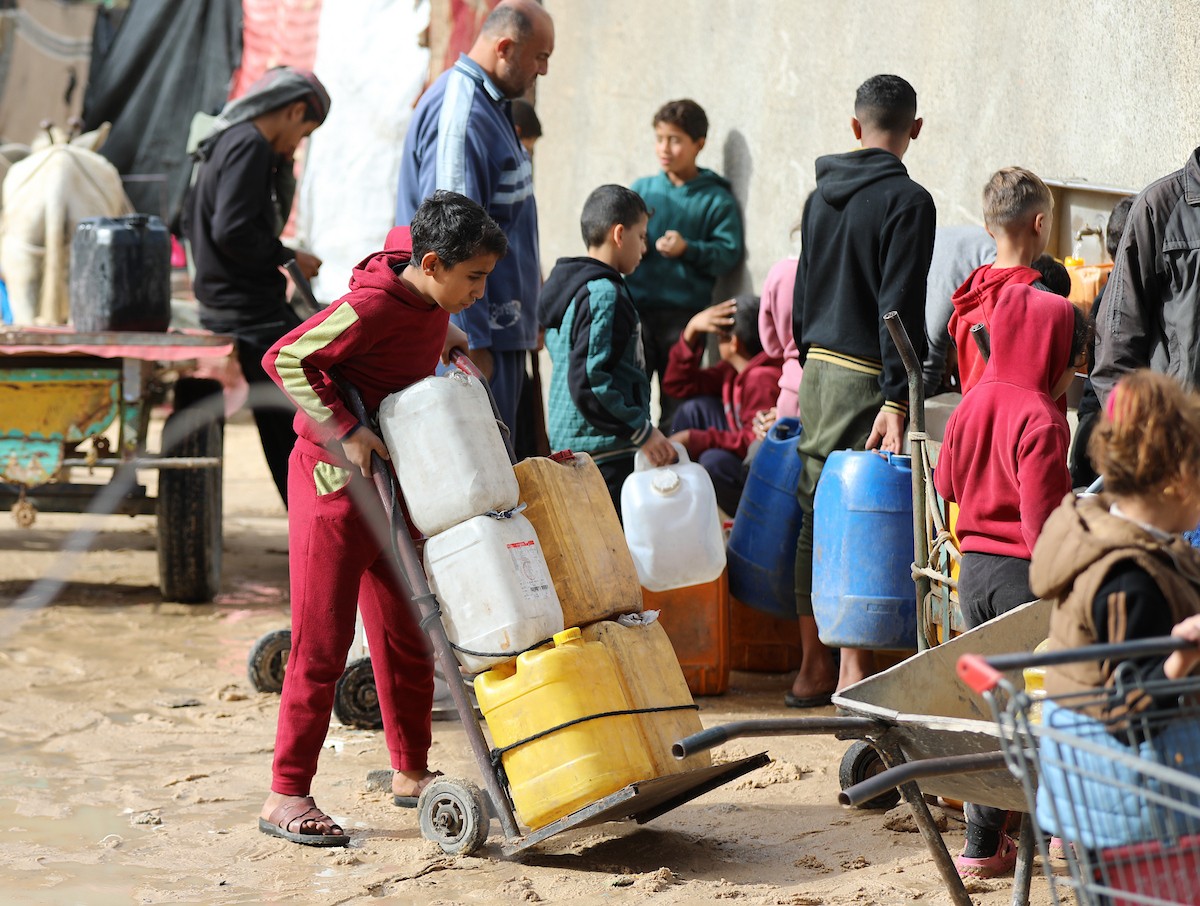 يتجمع الفلسطينيون لتلقي مياه الشرب مجانًا في مخيم البريج للاجئين، في ظل تفاقم أزمة نقص المياه وتدهور البنية التحتية، 21 ديسمبر/كانون الأول 2025. صورة: رمزي أبو عامر