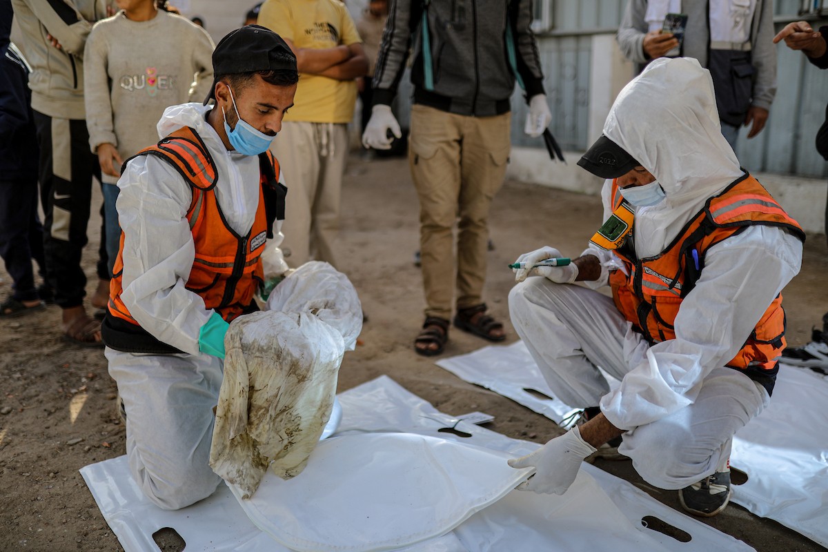 منقذون ومتطوعون فلسطينيون يستخرجون جثث ضحايا الحرب من مقبرة مؤقتة داخل المستشفى العربي المعمداني بمدينة غزة، ليعاد دفنها