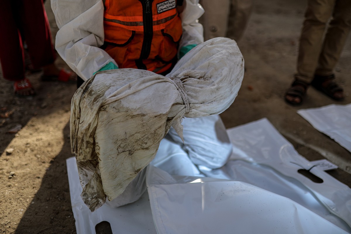 منقذون ومتطوعون فلسطينيون يستخرجون جثث ضحايا الحرب من مقبرة مؤقتة داخل المستشفى العربي المعمداني بمدينة غزة، ليعاد دفنها